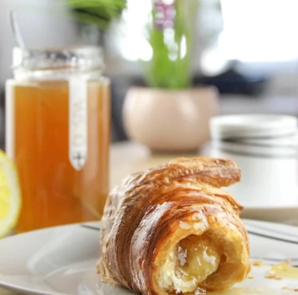 Zitronenkonfitüre mit einem Croissant in der früh